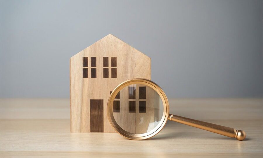 Small wooden house and magnifying glass