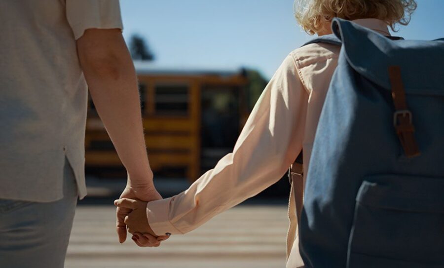 a dad holding his son's hand, walking to school